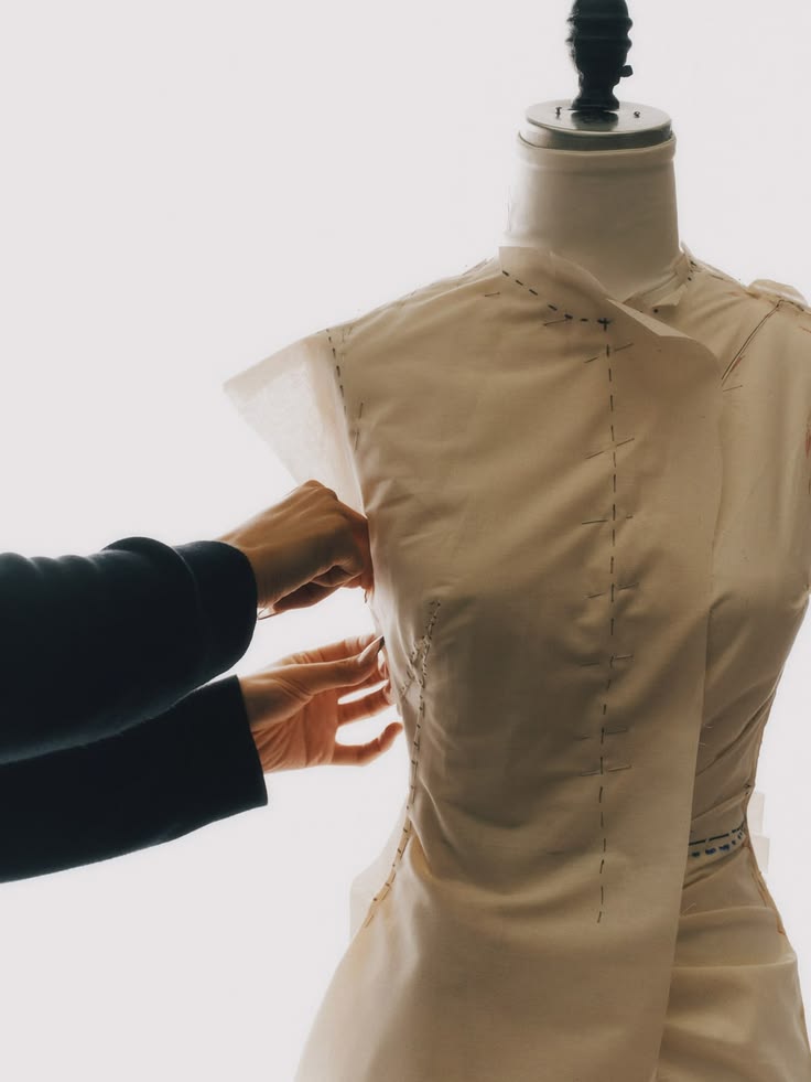 Manos montando una prenda hilvanada sobre un maniquí