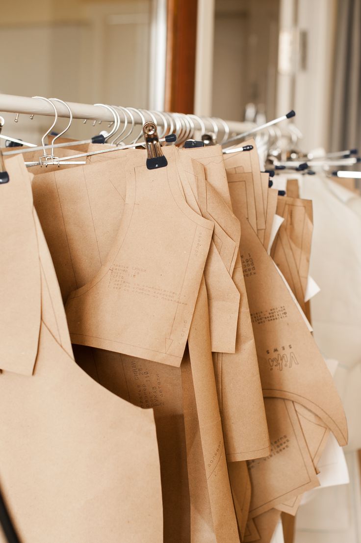 Patrones de papel kraft colgados de una barra con pinzas en un taller de costura