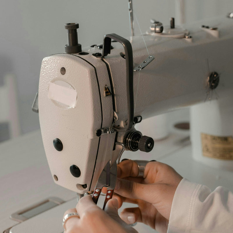 Manos enhebrando una máquina de coser en el taller